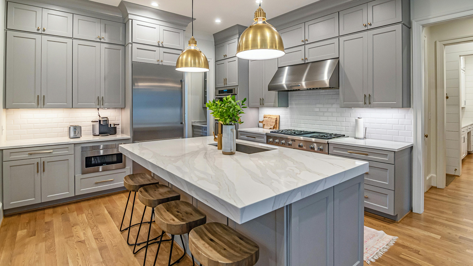 Custom gray shaker kitchen with brass pendant lighting, marble waterfall island and white oak floors in Parksville, BC