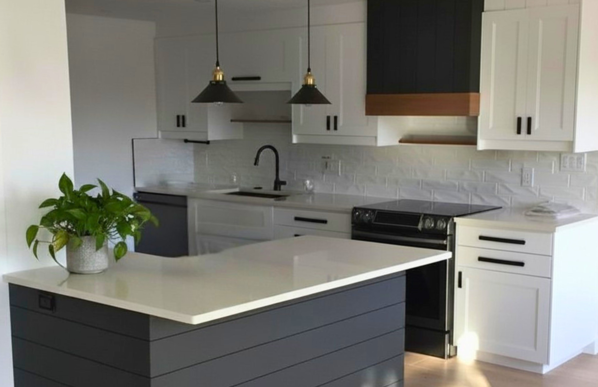 White shaker kitchen with charcoal shiplap island, black cone pendants and a dark shiplap range hood with wood-wrapped shelving